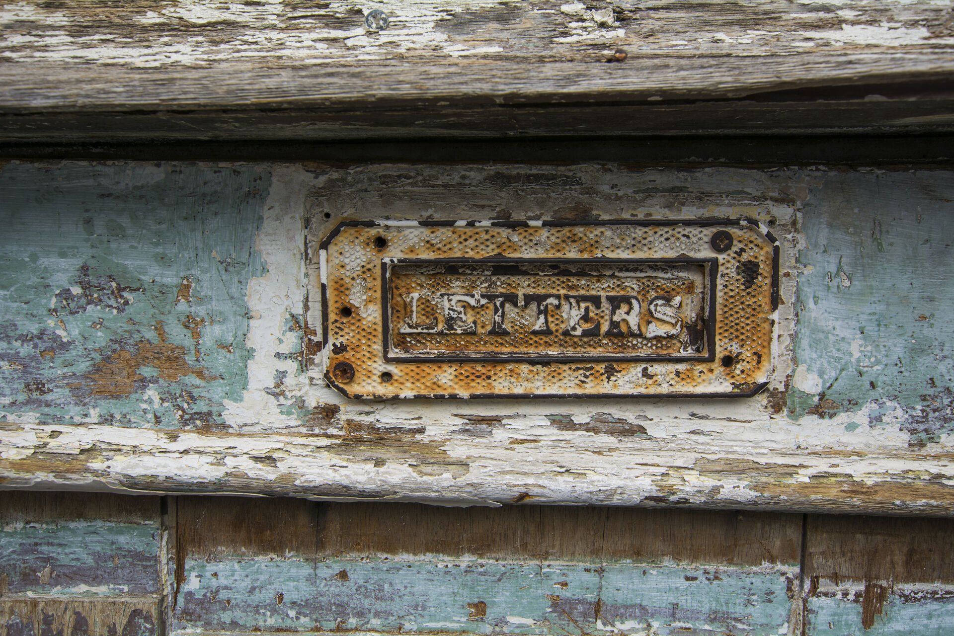 Brass letter slot in a weathered timber door