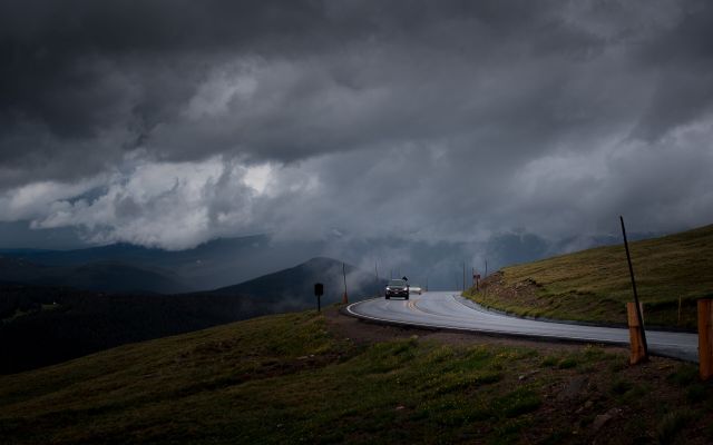 Car on a winding hill road under heavy cloud
