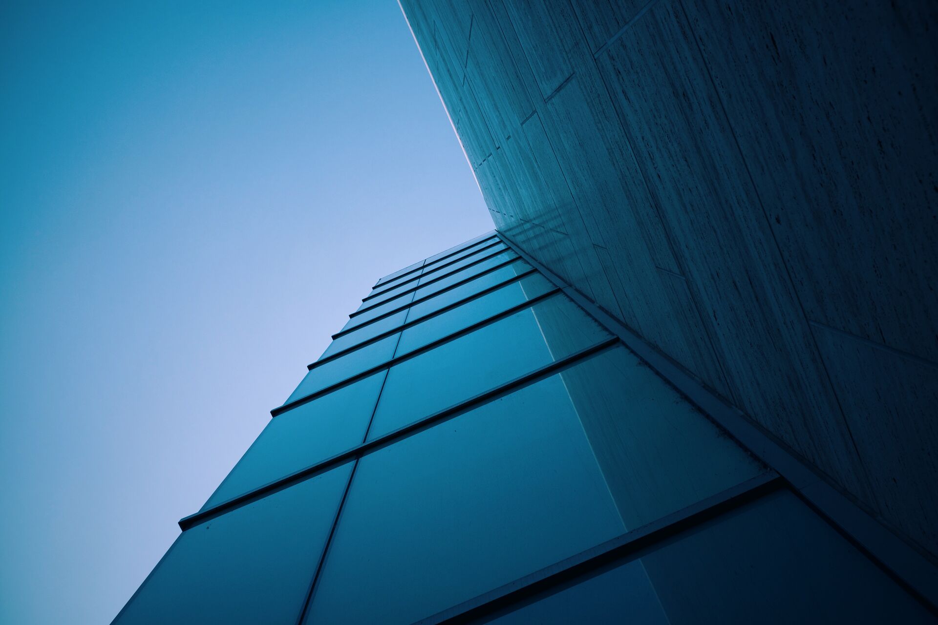 Corner of a glass office building against a blue sky