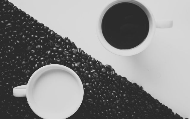 Two cups of coffee seen from above, one on coffee beans
